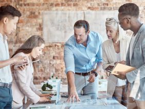 Group of diverse architects discussing plans, blueprints and schematics during a meeting in their office boardroom. Business people brainstorming and planning their upcoming project development